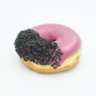Viscous Hibiscus Doughnut Ring doughnut with light purple hibiscus flavored icing and chocolate sprinkles on the left half