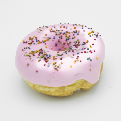 A raised yeast ring doughnut, dipped in strawberry icing, sprinkled with colorful non-pareil