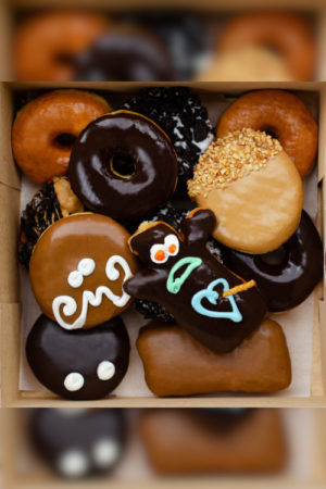 Top down shot of a dozen vegan Voodoo Doughnuts in a doughnut box.