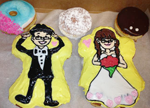 Two doughnuts shaped and frosted to look like a bride and groom