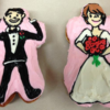 Two Doughnuts shaped and frosted to look like a traditional groom and bride