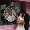The Whole Shebang Wedding kissing by Voodoo Doughnut Logo