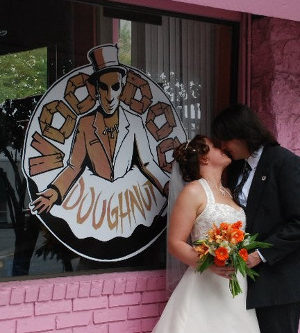 The Whole Shebang Wedding kissing by Voodoo Doughnut Logo