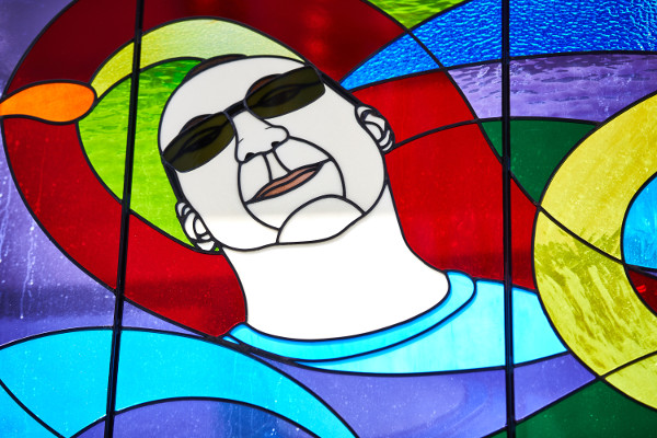 Stained glass window of Cat Daddy's face with colorful swirly background
