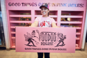 Universal Orlando Voodoo Doughnut Pink Box Close up shot of pink Voodoo Doughnut box held by a woman in the background
