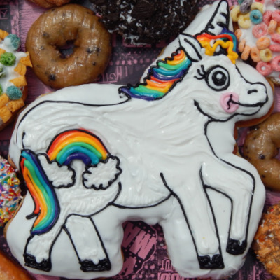 Doughnut in the shape of a Unicorn with white icing and rainbow decorations