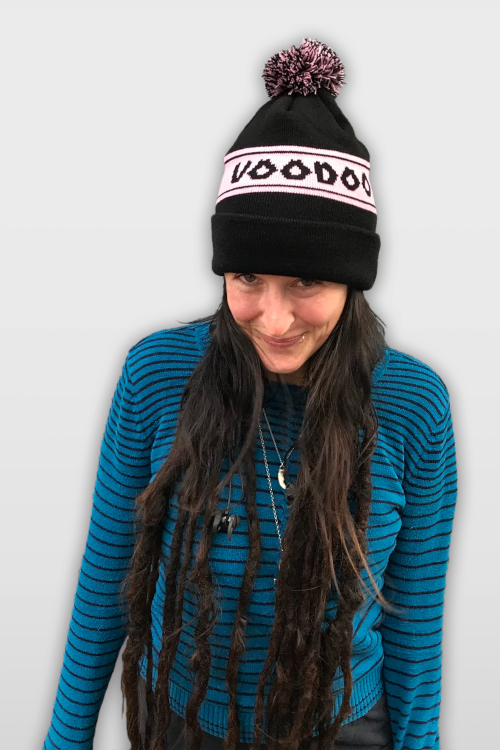 Woman wearing black beanie with pink band with the words Voodoo Doughnut.