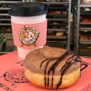 coffee cup with Voodoo Logo and Nossa Familia Coffee Doughnut sitting on a pink doughnut box
