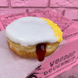 Round doughnut with white icing, lemon sprinkles and cherry filling