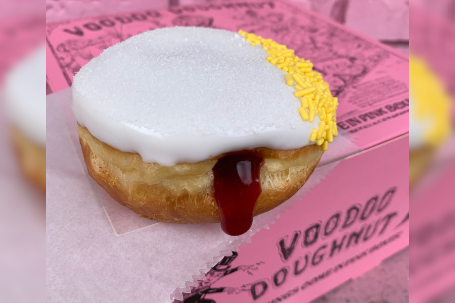 Round doughnut with white icing, lemon sprinkles and cherry filling
