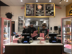 Staff preparing boxes behind the counter with a view of the menu board