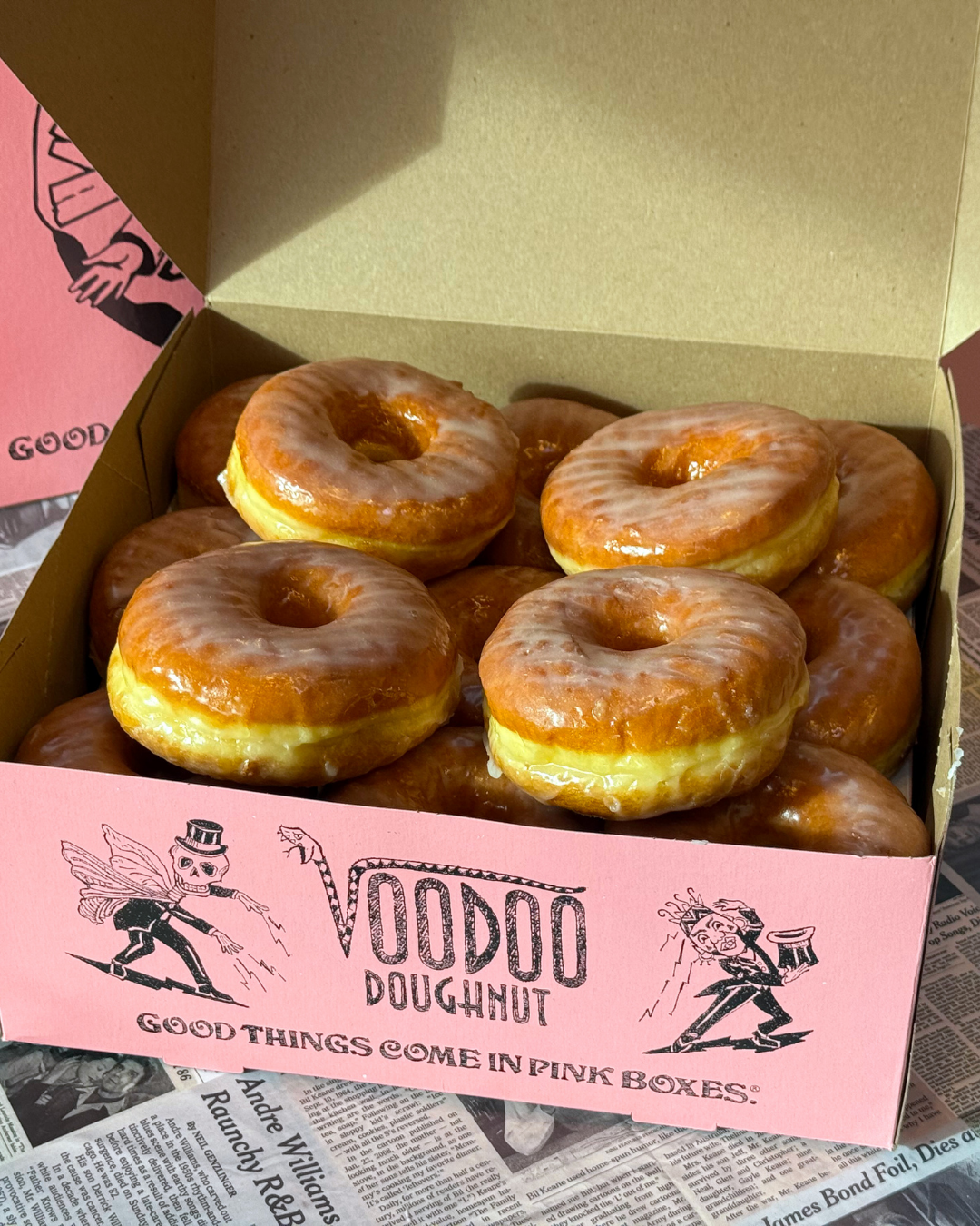 pink voodoo doughnut box filled with raised glazed doughnuts